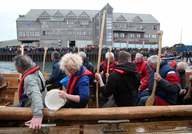 Crew in Britain's first ever full-size reconstructed sea-going Bronze Age boat, bail out water as they prepare to paddle out to sea near to the National Maritime Museum as it makes its maiden voyage on March 6, 2013 in Falmouth, England. With a crew of of 18, equipped with Bronze-Age-style wooden paddles, the 15 metre long experimental vessel – a replica of the sort of craft used for long-distance trade between Britain and the continent 4000 years ago – will be used to test prehistoric seafaring methods in a project in collaboration with the University of Exeter and the Falmouth-based National Maritime Museum Cornwall. (Photo by Matt Cardy)