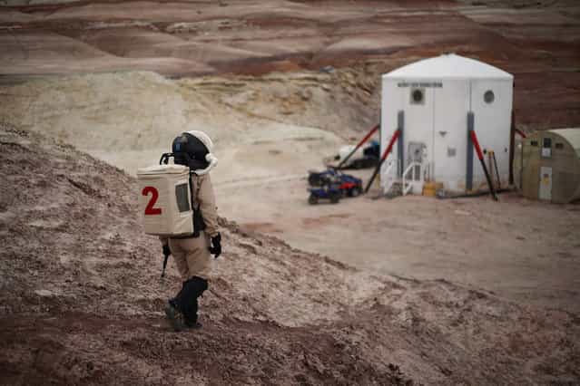 Csilla Orgel, a geologist of Crew 125 EuroMoonMars B mission, makes her way back to the Mars Desert Research Station (MDRS) in the Utah desert March 3, 2013. The MDRS aims to investigate the feasibility of a human exploration of Mars and uses the Utah desert's Mars-like terrain to simulate working conditions on the red planet. Scientists, students and enthusiasts work together developing field tactics and studying the terrain. All outdoor exploration is done wearing simulated spacesuits and carrying air supply packs and crews live together in a small communication base with limited amounts of electricity, food, oxygen and water. Everything needed to survive must be produced, fixed and replaced on site. (Photo by Jim Urquhart/Reuters)