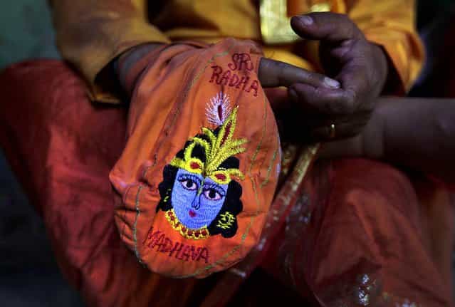 A priest prays holding a bag with an image of the Hindu God Krishna at the Ladali in Barsana. (Photo by Manish Swarup/Associated Press)