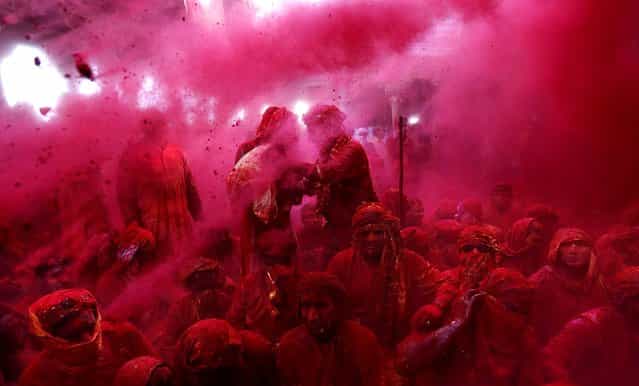 Men from the village of Nangaon are covered in colored powder as they sit on the floor during prayers at the Radha Temple. (Photo by Kevin Frayer/Associated Press)