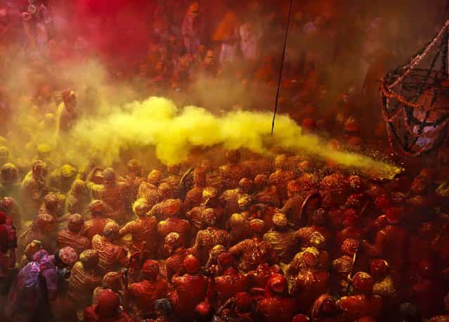 Hindu men from the village of Nandgaon are covered in colored powder as they sit on the floor during prayers at the Ladali before the procession for the Lathmar Holi festival. (Photo by Kevin Frayer/Associated Press)