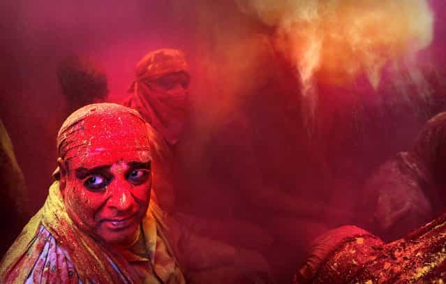 Hindu men from the village of Nangaon are covered in colored powder as they sit on the floor during prayers at the Ladali, or Radha temple, before the procession for the Lathmar Holi festival. (Photo by Kevin Frayer/Associated Press)
