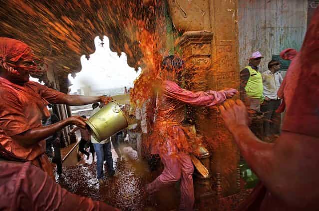 Villagers from Nandgaon throw colored water on the villagers from Barsana as they arrive at the Nandagram temple. (Photo by Manish Swarup/Associated Press)