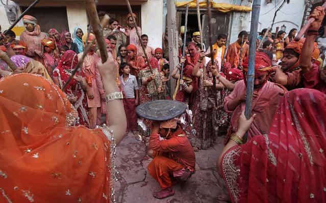 Indian women from Nandgaon hit villagers from Barsana. During Lathmar Holi the women of Nandgaon, the hometown of Krishna, beat the men from Barsana, the legendary hometown of Radha, consort of the Hindu God Krishna, with wooden sticks in response to their teasing as they depart the town. (Photo by Manish Swarup/Associated Press)
