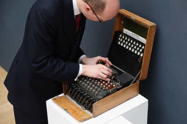 An employee at Christie's auction house examines an Enigma cipher machine on March 27, 2013 in London, England. The Enigma machine is expected to fetch 60,000 GBP when it features in Christie's [Travel, Science and Natural History] sale, which is to be held on April 24, 2013 in London. (Photo by Oli Scarff)