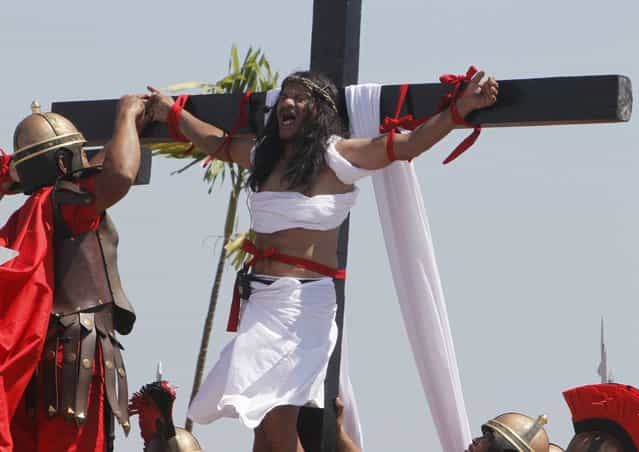 Ruben Enaje, 52, who is portraying Jesus Christ for the 27th time, screams while a man playing a Roman soldier pulls out a nail from his palm after he was nailed on a wooden cross during a Good Friday crucifixion re-enactment in San Pedro Cutud town, Pampanga province, north of Manila March 29, 2013. About two dozen Filipinos were nailed to crosses on Good Friday in an extreme display of devotion that the Catholic church looks down upon as a form of folk religion but appears powerless to stop. Holy Week is celebrated in many Christian traditions during the week before Easter. (Photo by Romeo Ranoco/Reuters)