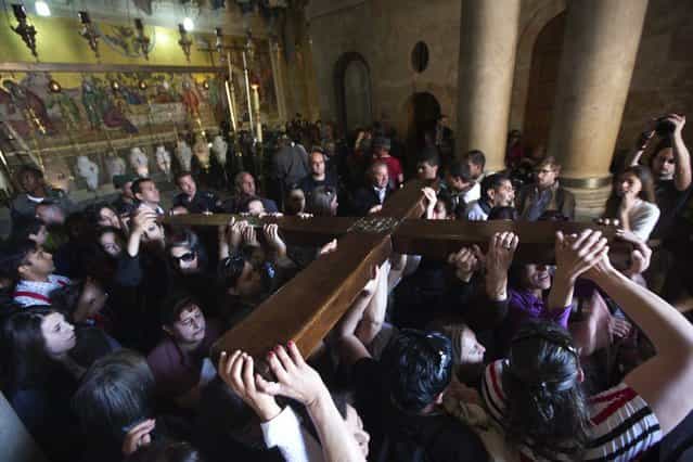 Worshippers carry a cross in the Church of the Holy Sepulchre on Good Friday during Holy Week, in Jerusalem's Old City March 29, 2013. Christian worshippers retraced the route Jesus took along Via Dolorosa to his crucifixion in the Church of the Holy Sepulchre. Holy Week is celebrated in many Christian traditions during the week before Easter. (Photo by Nir Elias/Reuters)