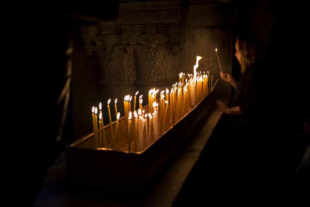 A Christian Catholic pilgrim lights a candle inside the Church of the Holy Sepulcher, traditionally believed to be the site of the crucifixion of Christ, in Jerusalem's Old City, Friday, March 29, 2013. Less than 2 percent of the population of Israel and the Palestinian territories is Christian, mostly split between Catholicism and Orthodox streams of Christianity. Christians in the West Bank wanting to attend services in Jerusalem must obtain permission from Israeli authorities. Israel's Tourism Ministry said it expects some 150,000 visitors in Israel during Easter week and the Jewish festival of Passover, which coincide this year. (Photo by Bernat Armangue/AP Photo)