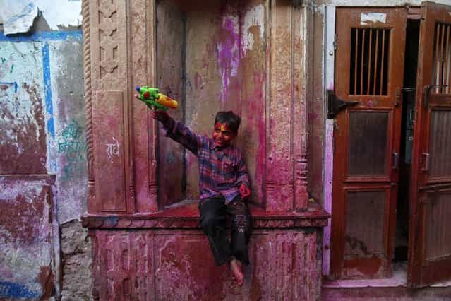 A boy plays with a water pistol during holi celebrations in a lane near the Bankey Bihari temple in Vrindavan in the northern Indian state of Uttar Pradesh March 25, 2013. Holi, also known as the Festival of Colours, heralds the beginning of spring and is celebrated all over India. (Photo by Vivek Prakash/Reuters)
