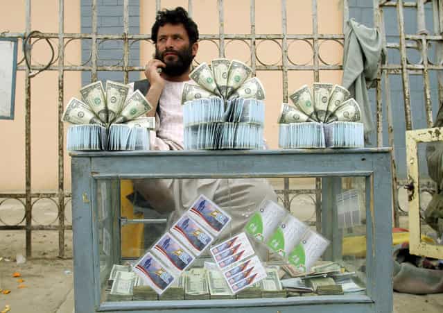 An Afghan seller of U.S. dollar notes waits for customers in Kandahar, southern Afghanistan, Tuesday, March 26, 2013. Residents of Kandahar complain of few jobs despite heavy international investment in the country since the collapse of the Taliban in 2001. (Photo by Allauddin Khan/AP Photo)