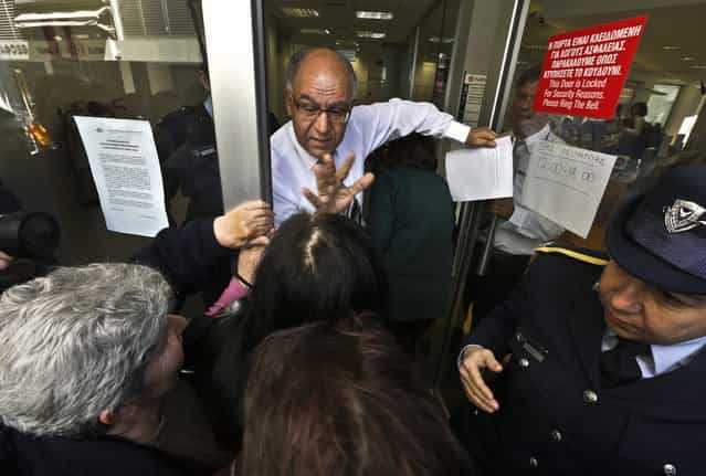 A Laiki Bank manager tries to calm depositors waiting for the opening of the bank's branch in Nicosia March 28, 2013. Banks in Cyprus opened their doors on Thursday for the first time in almost two weeks, with tight controls on transactions to prevent a run on deposits after the island was forced to accept a stringent EU rescue package to avert bankruptcy. (Photo by Yannis Behrakis/Reuters)