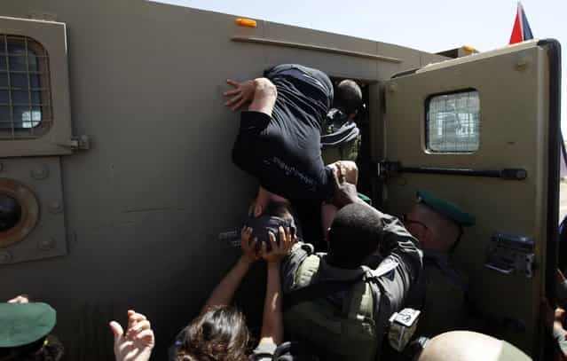 A foreign activist tries to escape from a jeep after he was detained by Israeli border policemen on suspicion of attacking an officer during minor clashes at a rally marking Land Day in the West Bank village of al-Tuwani, south of Hebron March 29, 2013. Palestinian, Israeli and foreign activists took part in the rally which marks the annual commemorations in Israel of six Arab citizens killed by police in 1976 during protests against land confiscations in northern Israel's Galilee region. (Photo by Ammar Awad/Reuters)