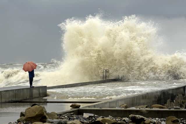 A woman stands on a pier under an umbrella during a storm in a Russian Black Sea resort of Sochi on March 24, 2013. (Photo by Mikhail Mordasov/AFP Photo)