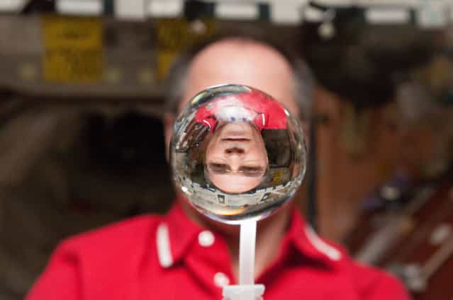 NASA astronaut Kevin Ford, Expedition 34 commander, watches a water bubble float freely between him and the camera, showing his image refracted, in the Unity node of the ISS, on January 30, 2013. (Photo by Reuters/NASA/The Atlantic)