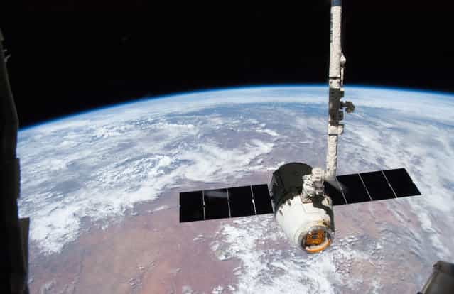 The release the SpaceX Dragon-2 spacecraft from the International Space Station on March 26, 2013. The spacecraft, filled with experiments and old supplies, is in the grasp of the Space Station Remote Manipulator System's robot arm or CanadArm2 after it was undocked from the orbital outpost. Forming the backdrop for this image is western Namibia. The Dragon was scheduled to make a landing in the Pacific Ocean, off the coast of California later in the day. (Photo by NASA/The Atlantic)