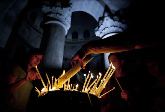 Christian worshippers light candles during the Sunday Easter mass at the Church of the Holy Sepulcher, traditionally believed to be the site of the crucifixion of Christ, in Jerusalem's Old City, Sunday, March 31, 2013. (Photo by Sebastian Scheiner/AP Photo)