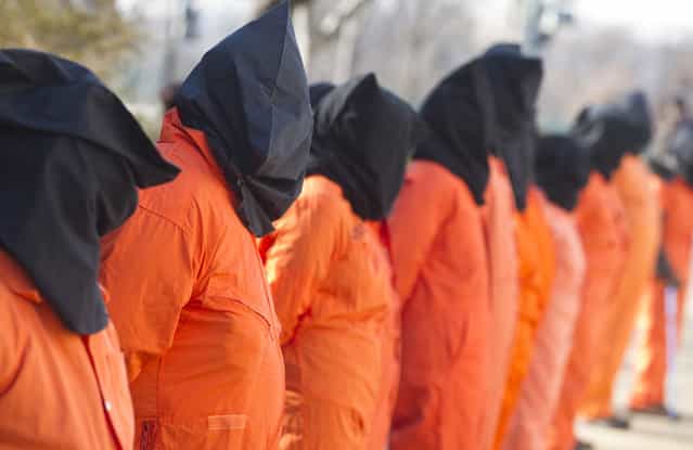 Protestors wear orange prison jumpsuits and black hoods on their heads during protests against holding detainees at the military prison in Guantanamo Bay during a demonstration on Capitol Hill in Washington, D.C., on January 8, 2013. (Photo by Saul Loeb/AFP Photo /The Atlantic)