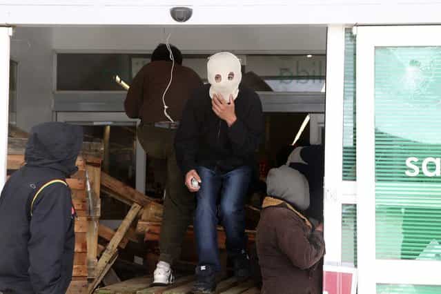 A masked looter walks leaves a supermarket in the Argentine city of San Carlos de Bariloche, on December 20, 2012. About 150 masked people looted a supermarket after breaking its windows, gates and perimeter surrounding the area, according to local media. The looters stoned the police who retaliated with tear gas. (Photo by Chiwi Giambirtone/Reuters /The Atlantic)