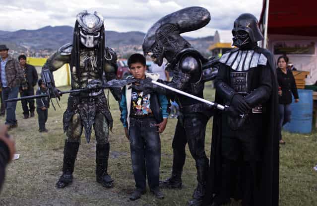 A boy poses for a picture with people wearing costumes of famous sci-fi movies during the Canaan fair which is part of the Holy Week celebrations in Ayacucho, Peru, on March 28, 2013. (Photo by Rodrigo Abd/AP Photo /The Atlantic)