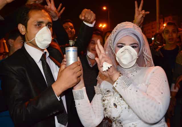 Revolutionary activist Mohammed Magdy and his bride, wear masks against tear gas and jointly hold a used tear gas container, celebrating their wedding in Revolution Square, the center of weeks of anti-government clashes, in the Nile Delta city of Mansoura, Egypt, on March 4, 2013. Protesters in Mansoura, and other Egyptian cities have been calling for civil disobedience campaigns, or work stoppages, to bring down President Mohammed Morsi who they accuse along with the Muslim Brotherhood of trying to monopolize power and of reneging on promises of reform. (Photo by AP Photo /The Atlantic)