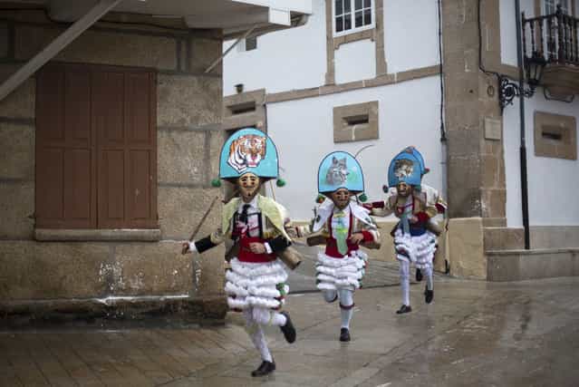 Carnival revelers dressed as [Peliqueiros] run through a street in Spain's northwestern village of Laza, on February 10, 2013. [Peliqueiros] or ancient tax collectors, pursued villagers through the streets ringing their cowbells and hitting villagers with their sticks. (Photo by Miguel Vidal/Reuters /The Atlantic)