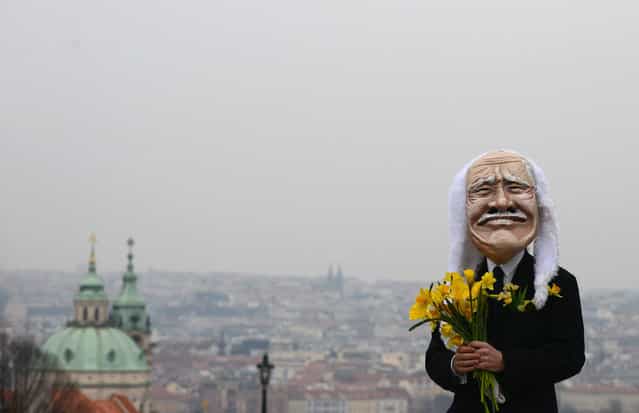 A man wearing a mask of Czech President Vaclav Klaus holds flowers during a march celebrating the end of his presidency, on March 7, 2013 at the Charles Bridge in Prague. (Photo by Michal Cizek/AFP Photo /The Atlantic)