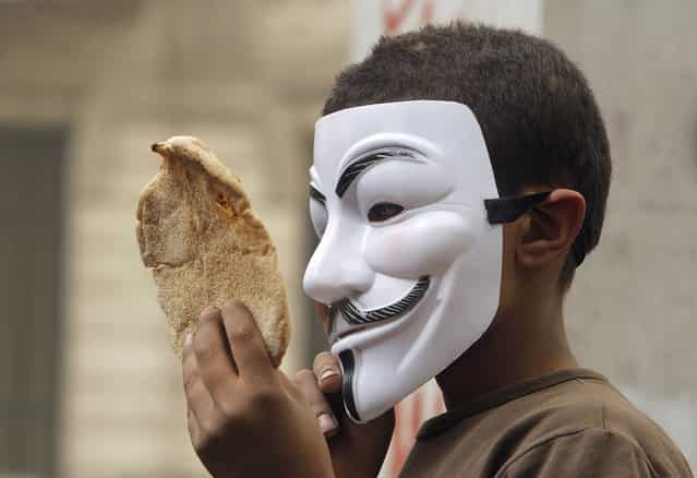 An Egyptian boy wearing a Guy Fawkes Mask holds bread, a symbol of poverty, during an anti-Muslim Brotherhood demonstration in Cairo, Egypt, on March 22, 2013. Thousands of protesters from different areas of Cairo marched on Friday to express their rejection of the Muslim Brotherhood and President Mohammed Morsi's rule. (Photo by Amr Nabil/AP Photo /The Atlantic)