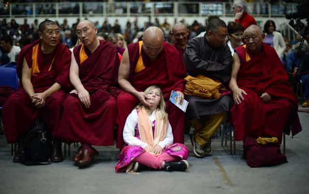 A girl sits by buddhist monks during a public meeting of the Tibetan spiitual leader, the Dalai Lama, after he was awarded the award of Minorities by province of Bolzano on April 11, 2013 in Trento. (Photo by Olivier Morin/AFP Photo)