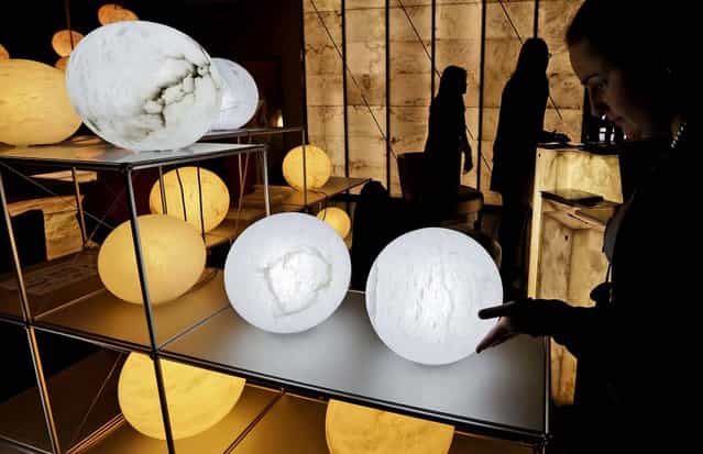 A woman touches an alabaster table lamp, by the Atelier Alain Ellouz factory, displayed at Milan's Design Fair, on April 9, 2013. (Photo by Luca Bruno/Associated Press)