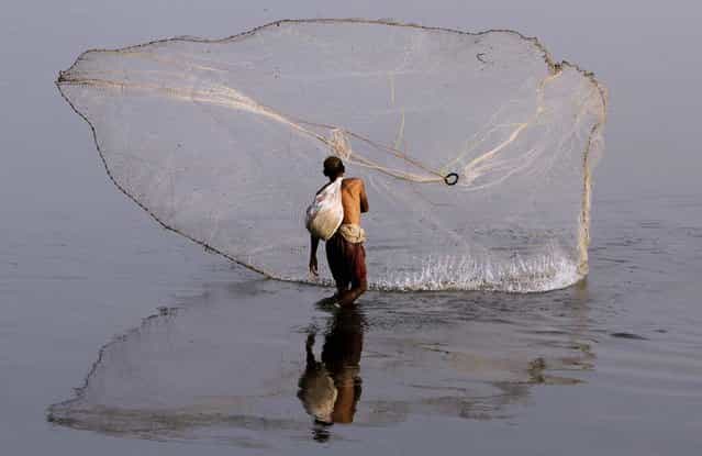A fisherman casts his net in the Ravi River in Lahore, Pakistan, on April 8, 2013. (Photo by K. M. Chaudary/Associated Press)
