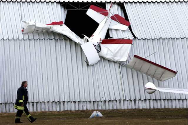 A firefighter passes a hangar where a light plane crashed into the roof, killing the pilot, in Neustadt-Glewe, Germany, on April 8, 2013. (Photo by Jens Buettner/Dpa)