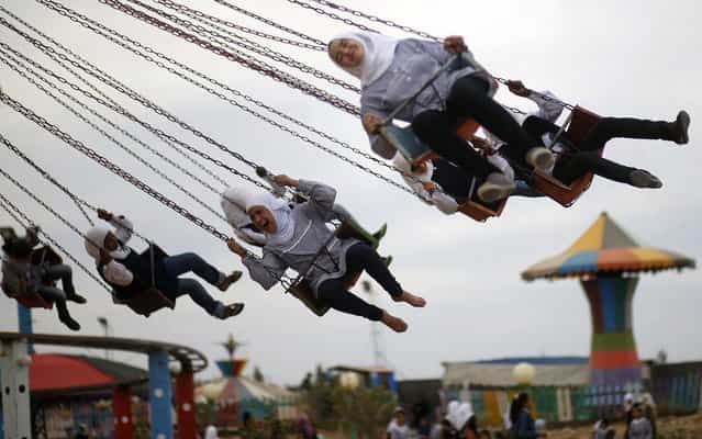 Palestinian girls have fun on a carousel amusement park built on land that was occupied by an Israeli camp in the central Gaza Strip, on April 11, 2013. (Photo by Mohammed Salem/Reuters)