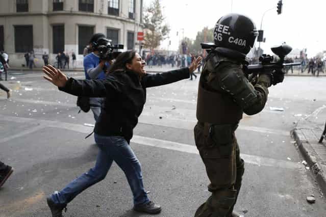A woman argues with a riot police officer as he uses a paint ball rifle to shoot at student protesters during a rally in which demonstrators demanded that the government make changes to the public state education system, in Santiago April 11, 2013. Chilean students and their supporters took back to the streets in a massive demonstration in demands of free and quality education for all. Thousands of people, led by both secondary and university student organizations, marched through downtown streets in the capital city as they continue to demand an educational overhaul in the latest student demonstration since the movement began in 2011. (Photo by Ivan Alvarado/Reuters)