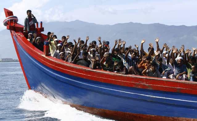 Ethnic Rohingya refugees from Myanmar wave as they are transported by a wooden boat to a temporary shelter in Krueng Raya in Aceh Besar April 8, 2013. About 74 Rohingya refugees, who were heading for Australia, were found stranded on Aceh island by Indonesian fishermen on Sunday, a police official said on Monday. (Photo by Junaidi Hanafiah/Reuters)