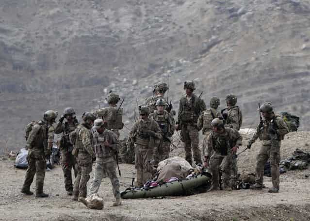 U.S. soldiers evacuate a dead body as they arrive to the scene after a NATO helicopter crashed in a field killing two American service members, near Gerakhel, eastern Afghanistan, Tuesday, April 9, 2013. The U.S.-led International Security Assistance Force said the cause of the crash is under investigation but initial reporting indicates there was no enemy activity in the area at the time. It did not immediately identify the nationalities of those killed. But a senior U.S. official confirmed they were Americans. (Photo by Rahmat Gul/AP Photo)