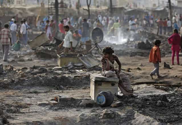 A local resident sits on a trunk amid the burnt debris of her hut after a fire broke out in a slum area in New Delhi April 12, 2013. Two people including a child, died on Friday after a fire broke out in a slum area on the outskirts of Delhi gutting several huts, local media reported. (Photo by Adnan Abidi/Reuters)