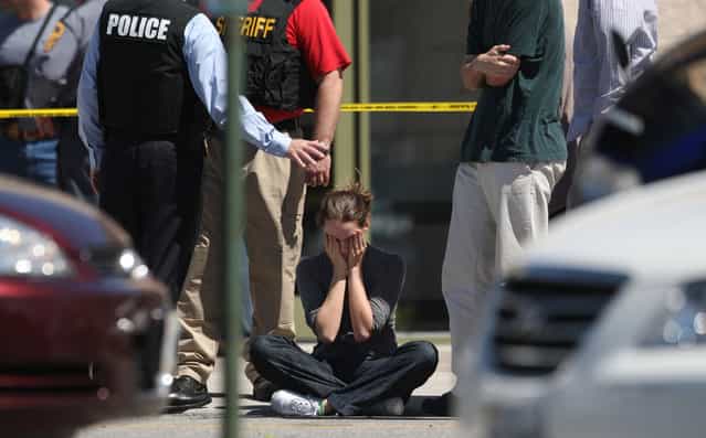 Clara Keller, of Blacksburg, Va. holds her head as she sits on the sidewalk near law enforcement officers outside the New River Valley Mall in Christiansburg, Va. on Friday, April 12, 2013. Officials say two women have been shot at the community college section of the mall and a suspect is in custody. (Photo by Daniel Lin/AP Photo/The Roanoke Times)