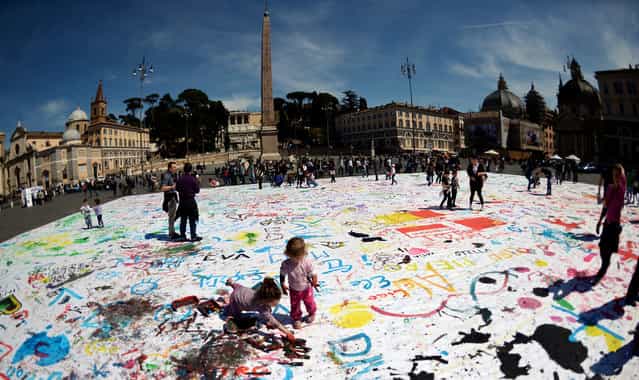 Children paint on a giant canvas in Rome's central Piazza del Popolo on April 7, 2013 during a performance named [What's good for families is good for the country] organised by the city's cultural association [Kitchen Art] aiming to make the Italian captial a family-friendly city. (Photo by Gabriel Bouys/AFP Photo)