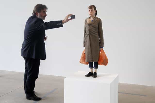 A visitor takes a picture of a sculpture entitled [Woman with Shopping, 2013] by artist Ron Mueck during the press day for his exhibition at the Fondation Cartier pour l'art contemporain in Paris April 15, 2013. (Photo by Charles Platiau/Reuters)