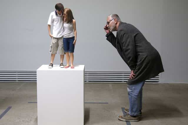 A visitor looks at a sculpture entitled [Young Couple, 2013] by artist Ron Mueck during the press day for his exhibition at the Fondation Cartier pour l'art contemporain in Paris April 15, 2013. The exhibition will run from April 16 to September 29, 2013. (Photo by Charles Platiau/Reuters)