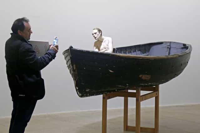 A visitor takes a picture of a sculpture entitled [Man in a Boat] (2002) by artist Ron Mueck during the press day for his exhibition at the Fondation Cartier pour l'art contemporain in Paris April 15, 2013. (Photo by Charles Platiau/Reuters)