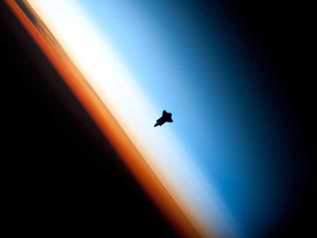 Though astronauts and cosmonauts often encounter striking scenes of Earth's limb, this unique image, part of a series over Earth's colorful horizon, has the added feature of a silhouette of the space shuttle Endeavour. The image was photographed by an Expedition 22 crew member prior to STS-130 rendezvous and docking operations with the International Space Station. Docking occurred at 11:06 p.m. (CST) on Feb. 9, 2010. The orbital outpost was at 46.9 south latitude and 80.5 west longitude, over the South Pacific Ocean off the coast of southern Chile, with an altitude of 183 nautical miles when the image was recorded. The orange layer is the troposphere, where all of the weather and clouds which we typically watch and experience are generated and contained. This orange layer gives way to the whitish Stratosphere and then into the Mesosphere. In some frames the black color is part of a window frame rather than the blackness of space. (Photo by NASA/Crew of Expedition 22) Though astronauts and cosmonauts often encounter striking scenes of Earth's limb, this unique image, part of a series over Earth's colorful horizon, has the added feature of a silhouette of the space shuttle Endeavour. The image was photographed by an Expedition 22 crew member prior to STS-130 rendezvous and docking operations with the International Space Station. Docking occurred at 11:06 p.m. (CST) on Feb. 9, 2010. The orbital outpost was at 46.9 south latitude and 80.5 west longitude, over the South Pacific Ocean off the coast of southern Chile, with an altitude of 183 nautical miles when the image was recorded. The orange layer is the troposphere, where all of the weather and clouds which we typically watch and experience are generated and contained. This orange layer gives way to the whitish Stratosphere and then into the Mesosphere. In some frames the black color is part of a window frame rather than the blackness of space. (Photo by NASA/Crew of Expedition 22)