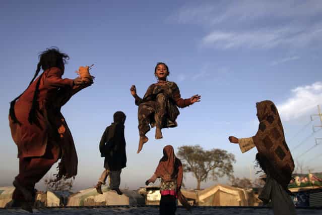 Pakistani children, who were displaced with their families by 2010 floods from a village in Pakistan's Sindh province, enjoy jumping on a trampoline, in a slum on the outskirts of Islamabad, Pakistan, Friday, February 8, 2013. (Photo by Muhammed Muheisen/AP Photo)
