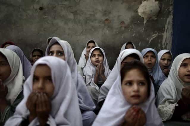 Pakistani schoolgirls, who were displaced with their families from Pakistan's tribal areas due to fighting between militants and the army, chant prayers during a class to pay tribute for five female teachers and two aid workers who were killed by gunmen on Tuesday, at a school in a slum on the outskirts of Islamabad, Pakistan, Thursday, January 3, 2013. (Photo by Muhammed Muheisen/AP Photo)