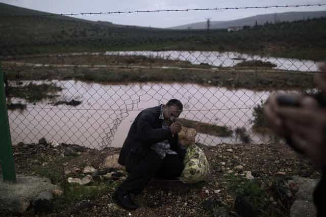 A Syrian refugee, crosses illegally to Turkey on the border fence, in Cilvegozu, Turkey, Thursday, December 20, 2012. (Photo by Muhammed Muheisen/AP Photo)
