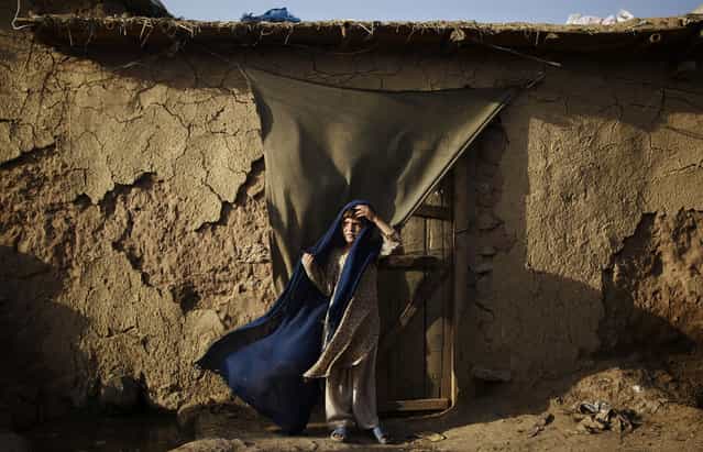 Afghan refugee Pasmeena Basheer, 6, holds on to her headscarf against the wind while standing in the doorway of a home in a slum area on the outskirts of Islamabad, on July 20, 2012. (Photo by Muhammed Muheisen/AP Photo)