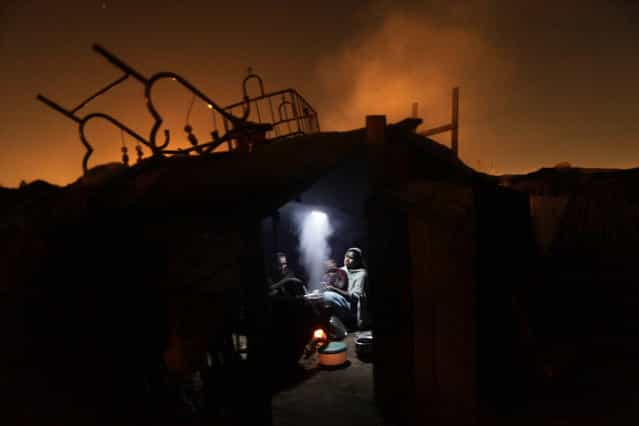 Pakistani women cook for their family using a fire inside their makeshift home, in a slum in Islamabad, on March 4, 2013. (Photo by Muhammed Muheisen/AP Photo)