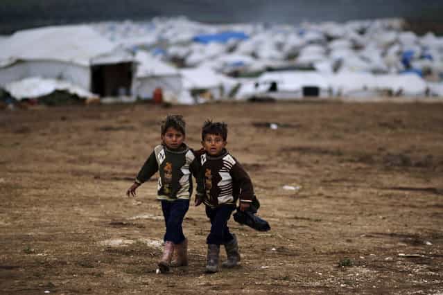 Syrian boys, whose family fled their home in Idlib, walk to their tent, at a camp for displaced Syrians, in the village of Atmeh, Syria, Monday, December 10, 2012. (Photo by Muhammed Muheisen/AP Photo)