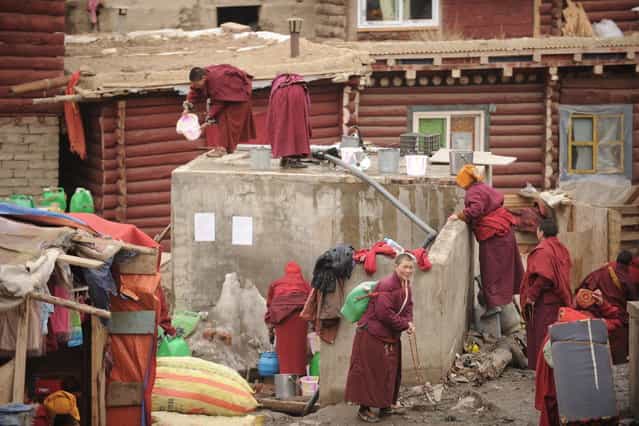 This photo taken on April 4, 2013 shows apprentice Buddhist monks and nuns collecting water in Seda Monastery, the largest Tibetan Buddhist school in the world, with up to 40,000 monks and nuns in residence for some parts of the year. Seda, known to Tibetans as Serthar is located in Ganzi prefecture in the west of China's Sichuan province and has become a hotbed of protests and violence since the Tibetan uprisings of March 2008. More than 110 Tibetans have set themselves alight since 2009, with most dying of their injuries, in demonstrations against what they view as Chinese oppression which Beijing rejects pointing to substantial investment in Tibet and other regions with large Tibetan populations, although critics say economic development has brought an influx of ethnic Han Chinese and eroded traditional Tibetan culture. (Photo by Peter Parks/AFP Photo)