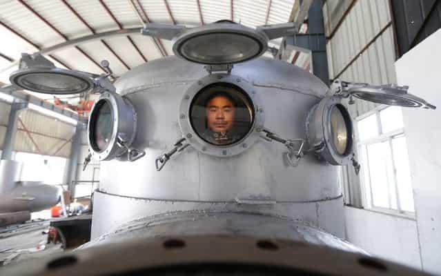 Zhang Wuyi sits in his newly made multi-seater submarine at his new workshop near an artificial pool in Wuhan, Hubei province, November 14, 2012. Zhang, a 37-year-old local farmer, who is interested in scientific inventions, has independently made seven miniature submarines with several fellow engineers, one of which was sold to a businessman in Dalian at a price of 100,000 yuan ($15,855) last October. The submarines, mainly designed for harvesting aquatic products, such as sea cucumber, have a diving depth of 20-30 metres (66-98 feet), and can travel for 10 hours, local media reported. (Photo by Reuters/Stringer)